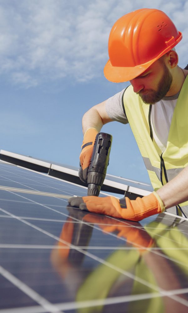 Male worker with solar batteries. Man in a protective helmet. Installing stand-alone solar panel system.